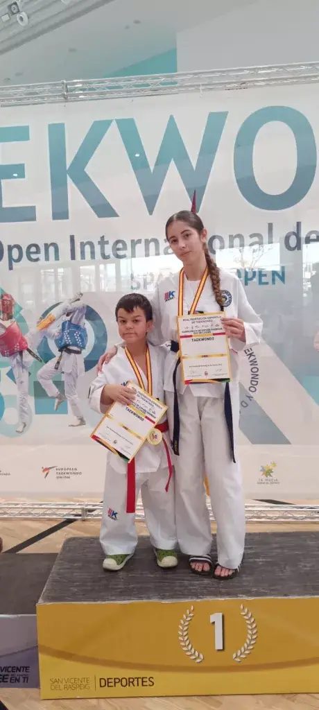 competidores sujetando un diploma con medallas colgadas